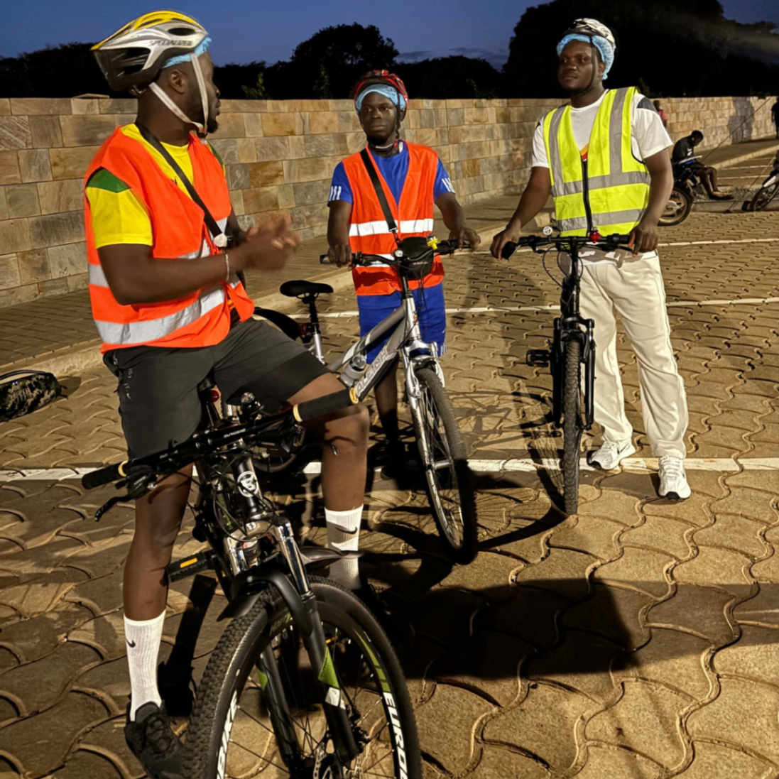 Semaine 4 · Trois riders After6 en gilets fluo échangeant avant le départ au crépuscule